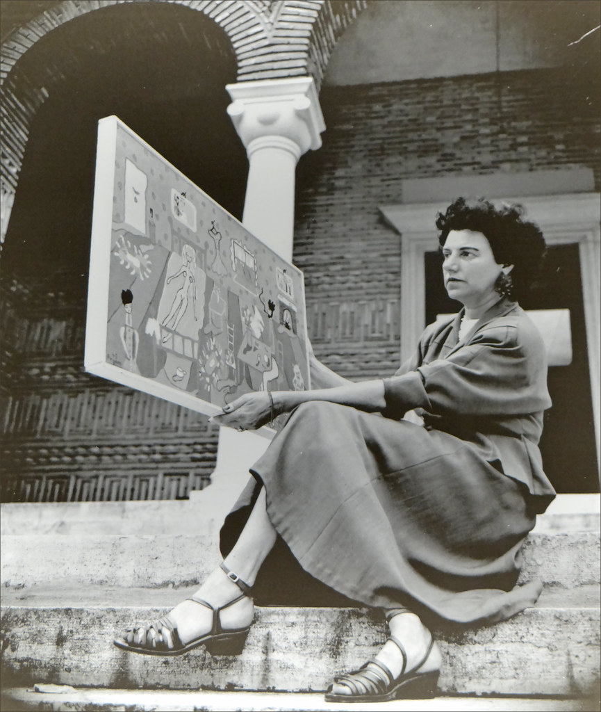 Peggy Guggenheim tenant l'oeuvre "Interior" de Pegeen Vail sur les marches du pavillon de la Grèce.